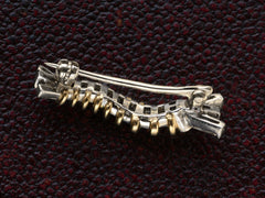 thumbnail of Reverse side of vintage white and yellow gold caterpillar brooch with ruby eyes and diamond baguettes, on dark textured background.