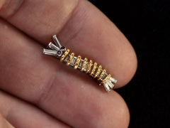 thumbnail of A vintage white and yellow gold caterpillar brooch with ruby eyes and diamond baguettes, on hand