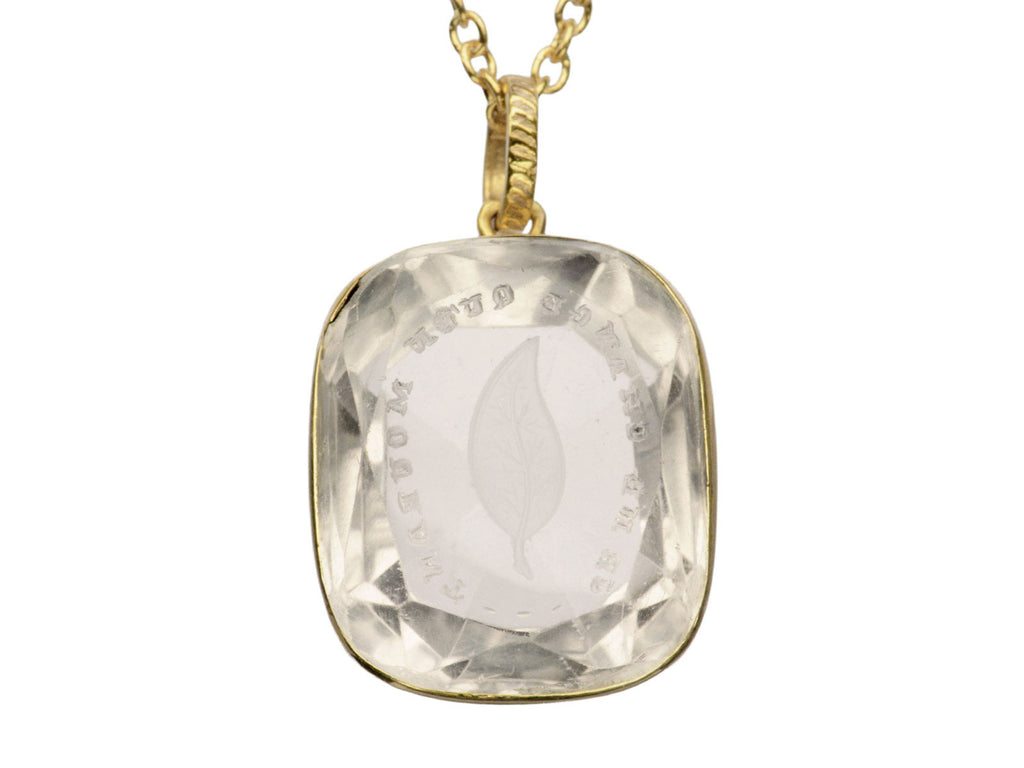 Detail of a c1820 Georgian era gold and crystal intaglio pendant carved with the image of an ivy leaf and the French phrase "Je Ne Change Qu'en Mourant." Shown on white background.