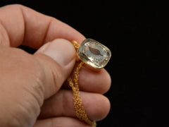 thumbnail of A c1820 Georgian era gold and crystal intaglio pendant carved with the image of an ivy leaf and the French phrase "Je Ne Change Qu'en Mourant." Shown in hand.