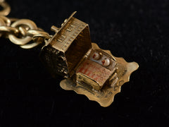 thumbnail of Detail view of yellow gold cottage charm opened to reveal a bed inside, on dark background.