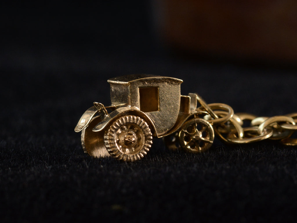 Detail view of yellow gold car charm on dark background.
