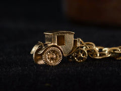 thumbnail of Detail view of yellow gold car charm on dark background.