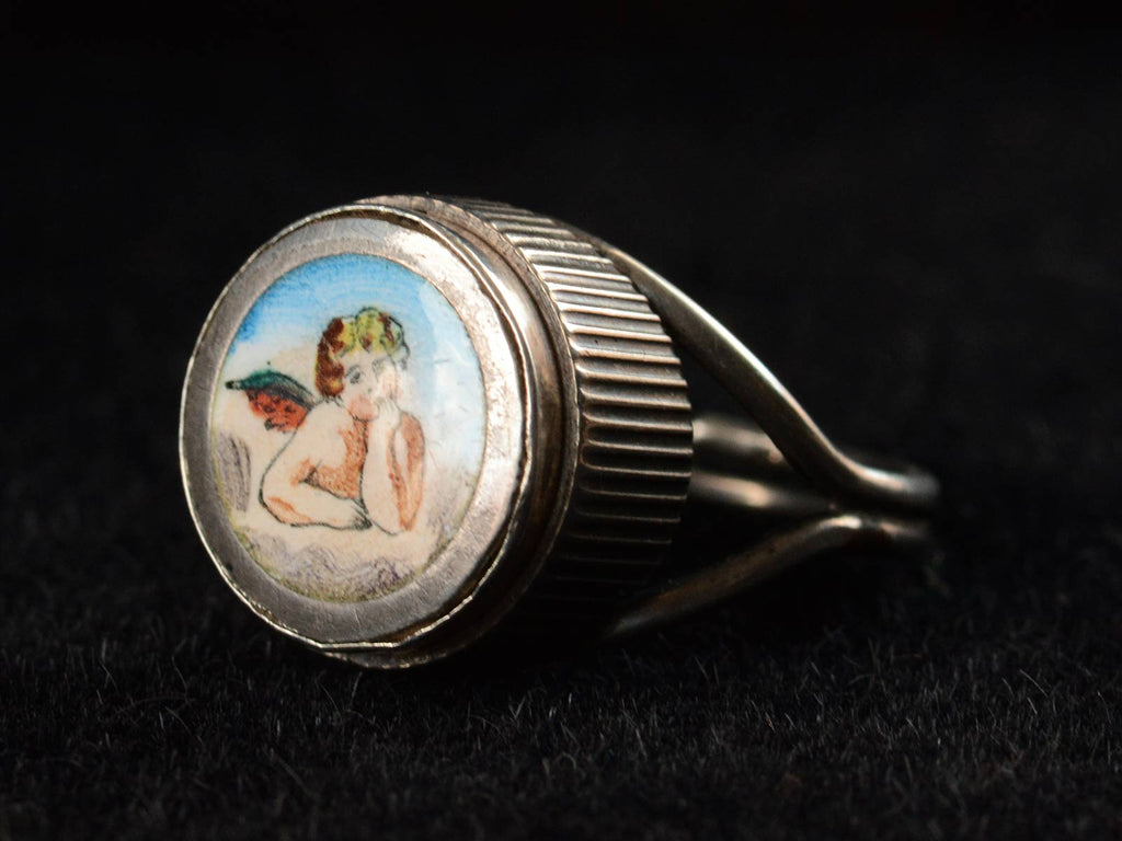 Right angle view of c1900 Silver and Enamel Cherub Ring (on dark background)