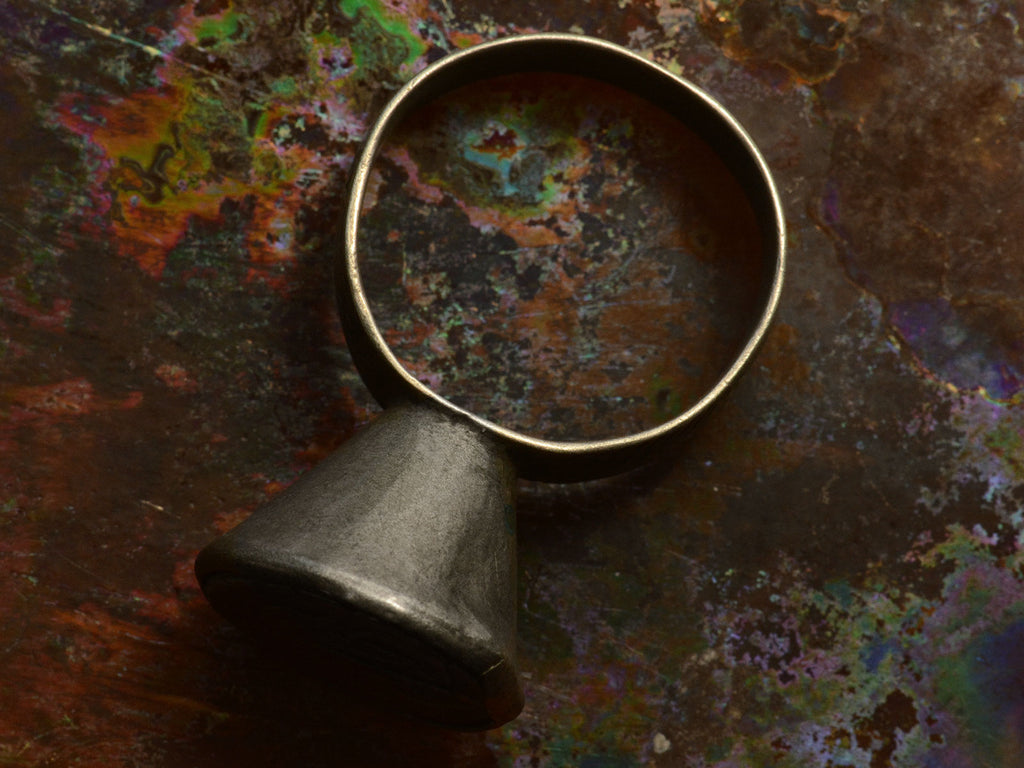 Side profile angle of Mughal Rupee Ring against colorful background.