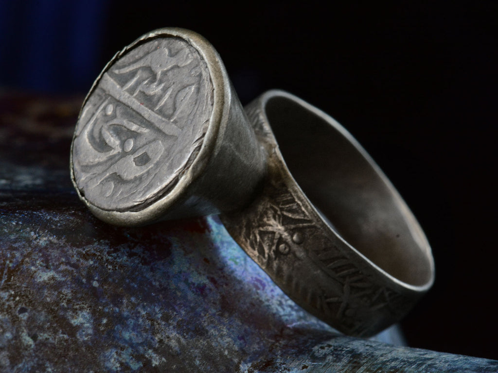 Angled view of Mughal Rupee Ring against colorful background.