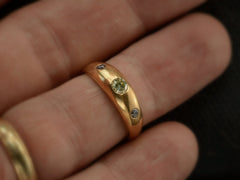 thumbnail of A rounded vintage 18k yellow gold ring flush set with a light greenish-yellow round diamond in between two smaller light pink diamonds, shown on finger