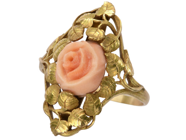 Angled view of 1930 ring with a coral rose surrounded by gold leaves and vines, shown on white background.