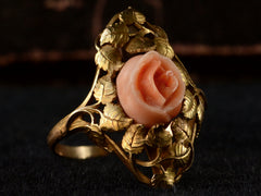 thumbnail of Left angled view of 1930 ring with a coral rose surrounded by gold leaves and vines, shown on black background.