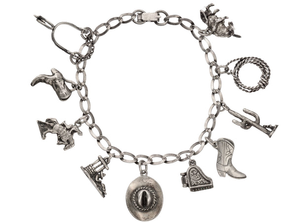 Vintage western-themed silver charm bracelet with a spur, two boots, a horse, a man sleeping in a sombrero, a cowboy hat, a piano with functioning lid, a cactus, a rope and a bull, on white background.