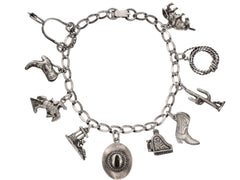 thumbnail of Vintage western-themed silver charm bracelet with a spur, two boots, a horse, a man sleeping in a sombrero, a cowboy hat, a piano with functioning lid, a cactus, a rope and a bull, on white background.