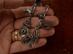 thumbnail of Silver western-themed charm bracelet, held in hand.