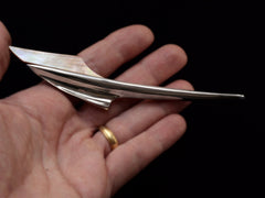 thumbnail of Abstract rocket-ship shaped sterling and abalone brooch on hand.
