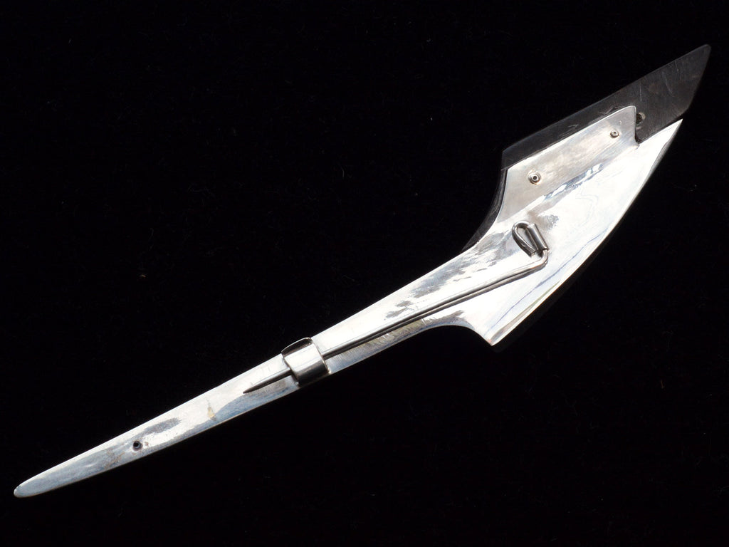 Reverse side of abstract rocket-ship shaped sterling and abalone brooch on black background.