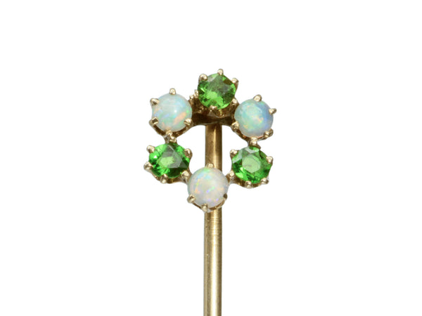 Detail of an antique yellow gold Victorian stick pin with three opals and three vivid green demantoid garnets arranged in a circle. Shown on white background.