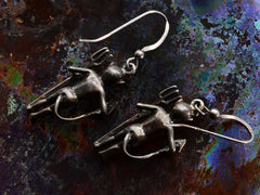 thumbnail of Reverse side of silver devil earrings with pitchforks, shown on dark textured background.