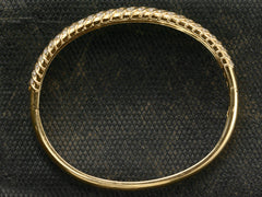 thumbnail of Side profile of a vintage 18K yellow gold bracelet set with three rows of round white diamonds in a fish-scale like pattern, shown on dark textured background.