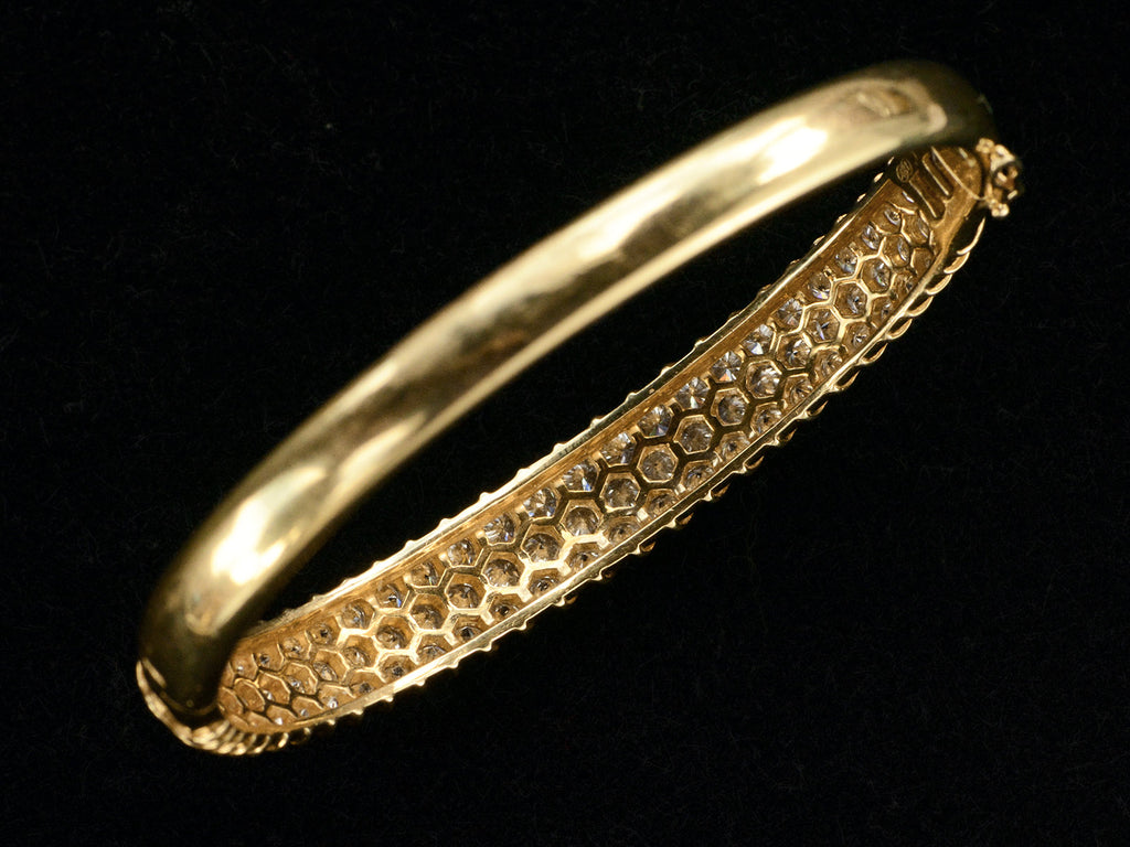 Underside of vintage 18K yellow gold bracelet set with three rows of round white diamonds in a fish-scale like pattern, shown on dark background.