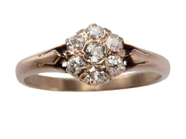 An antique rose gold Victorian ring with seven old European cut diamonds set in a cluster. Shown on white background.