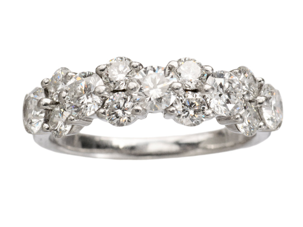 Band like platinum ring, half encrusted with a cluster of round diamonds, shown on white background. 