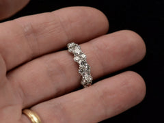 thumbnail of Band like platinum ring, half encrusted with a cluster of round diamonds, shown on finger.
