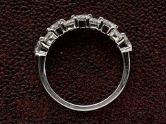 thumbnail of Side profile view of band like platinum ring, half encrusted with a cluster of round diamonds, shown on dark background. 