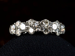 thumbnail of Front view of band like platinum ring, half encrusted with a cluster of round diamonds, shown on dark background. 