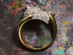 thumbnail of Side profile view of emerald-eyed diamond studded fish ring in platinum and yellow gold, shown on dark colorful background.