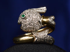 thumbnail of Front view of emerald-eyed diamond studded fish ring in platinum and yellow gold, shown on dark background.