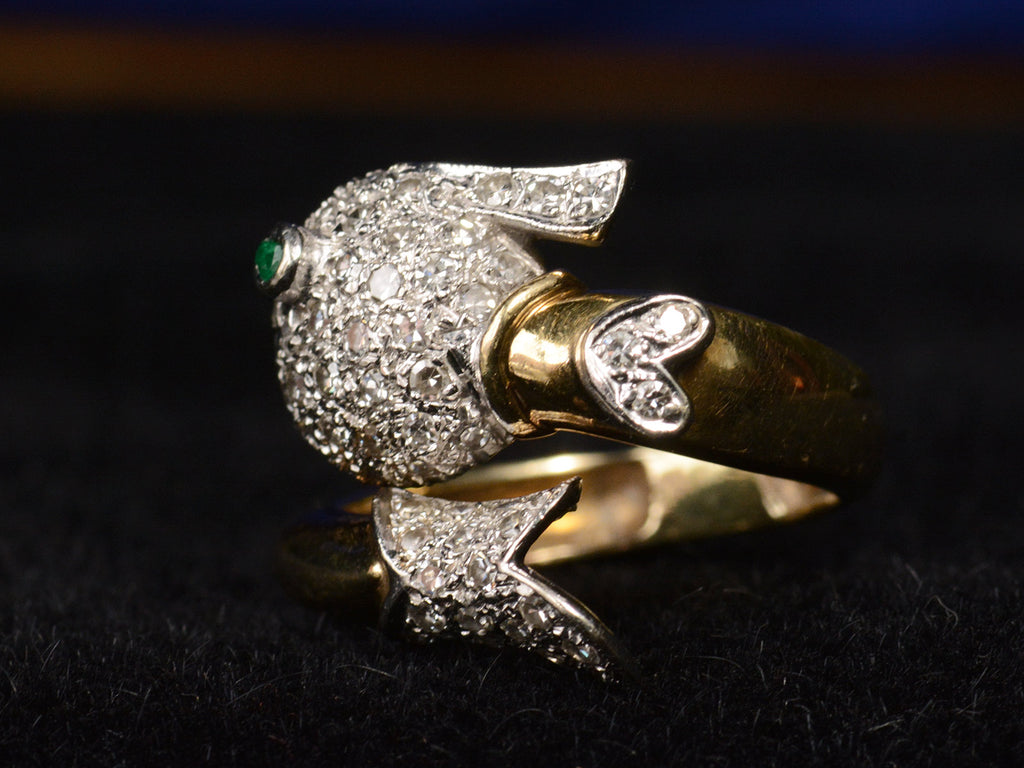Opposite tail detail view of emerald-eyed diamond studded fish ring in platinum and yellow gold, shown on dark background.