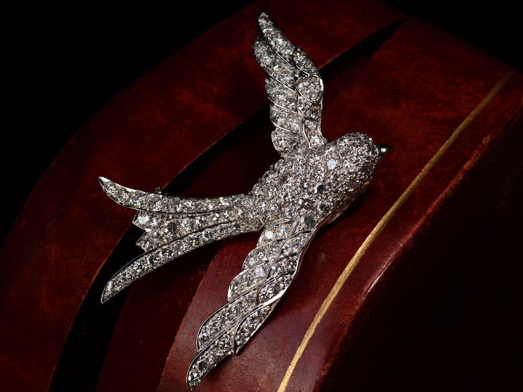 Vintage c1950 diamond-studded bird-shaped brooch shown perched on red leather box.
