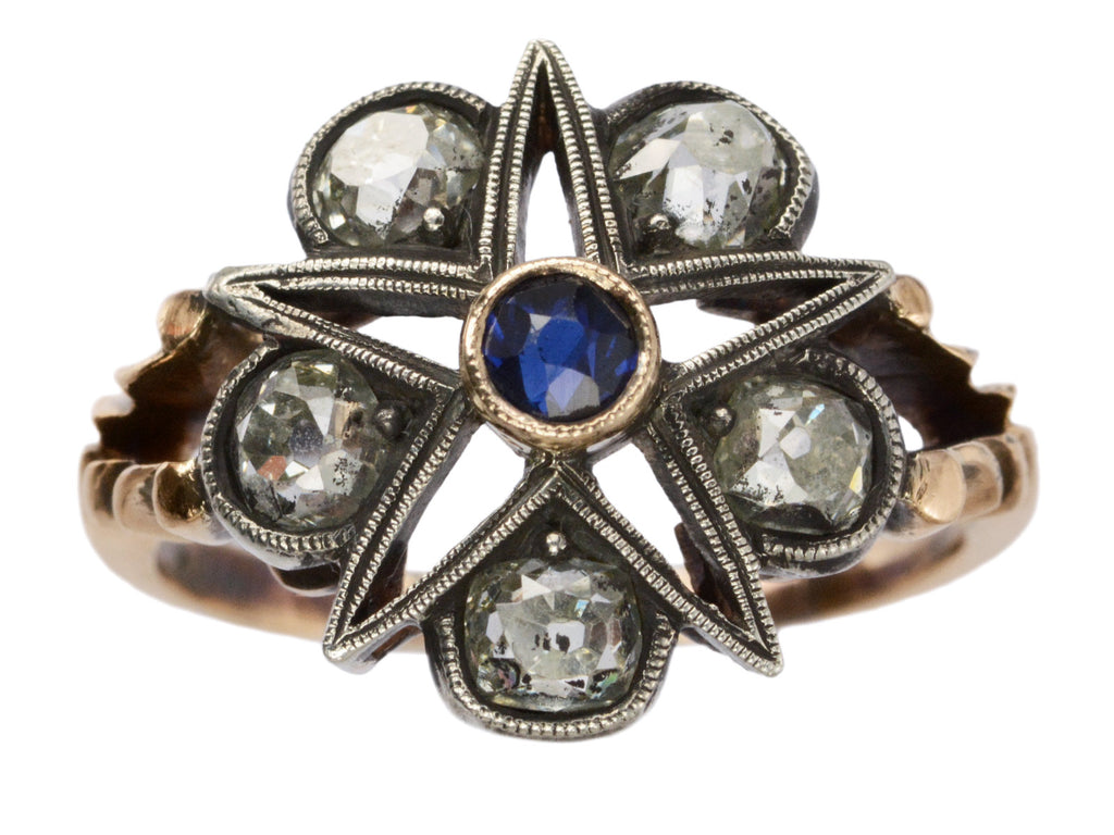 An antique silver-topped rose gold Victorian ring with a star design centering on a blue sapphire and old mine cut diamonds set in between each point. Shown on white background.