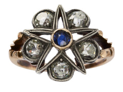 thumbnail of An antique silver-topped rose gold Victorian ring with a star design centering on a blue sapphire and old mine cut diamonds set in between each point. Shown on white background.
