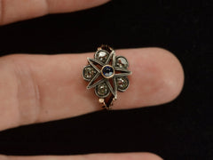 thumbnail of An antique silver-topped rose gold Victorian ring with a star design centering on a blue sapphire and old mine cut diamonds set in between each point. Shown on finger.