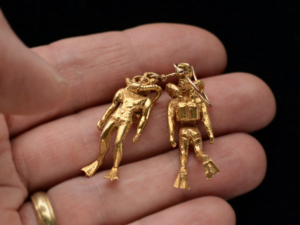 Pair of gold scuba diver earrings, on hand.