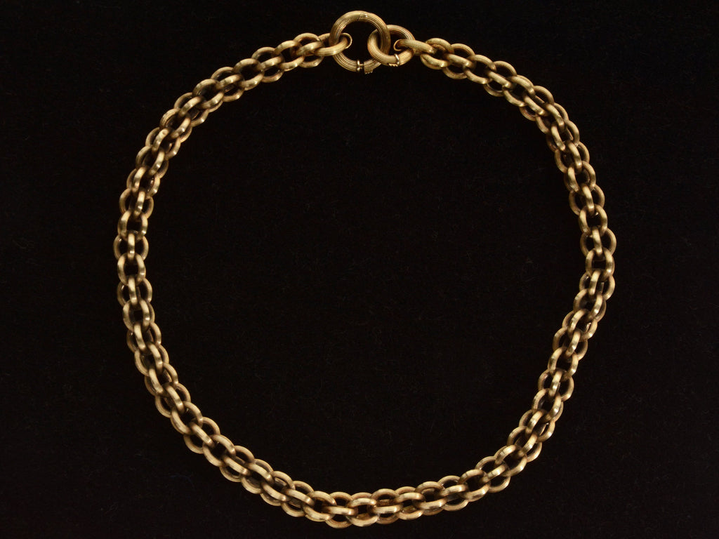 A double-link chain necklace with reeded texture, shown on dark background.