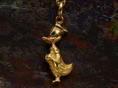 thumbnail of Reverse side of gold Donald Duck pendant with orange and blue enamel details shown on dark background.