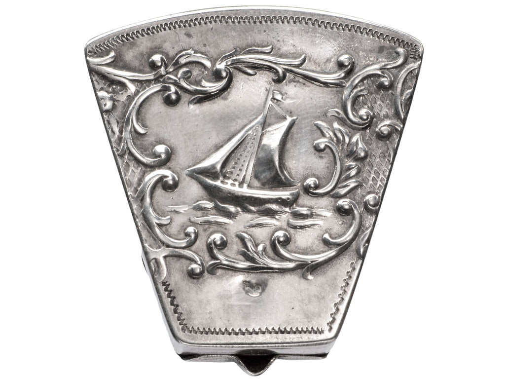 An antique silver wedge-shaped c1920 Dutch pillbox with the image of a sailboat, shown on white background.
