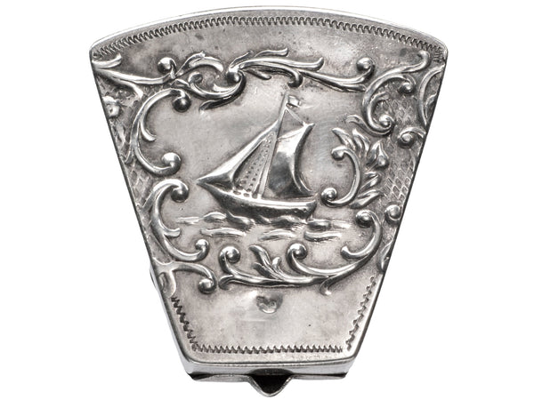 An antique silver wedge-shaped c1920 Dutch pillbox with the image of a sailboat, shown on white background.