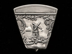 thumbnail of An antique silver wedge-shaped c1920 Dutch pillbox with the image of a windmill, shown on black background. A "HOLLAND" stamp is visible. 