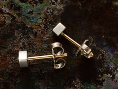 thumbnail of Sides of a pair of 0.19cttw square step cut white diamond stud earrings in platinum bezels with yellow gold posts, shown on dark textured background.