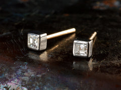 thumbnail of Angled front view of a pair of 0.19cttw square step cut white diamond stud earrings in platinum bezels with yellow gold posts, shown on dark textured background.