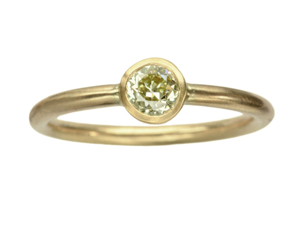 A simple EB Modern ring with a round light yellow diamond in a yellow gold bezel. Shown on white background.