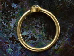 thumbnail of Side profile of simple EB Modern ring with a round light yellow diamond in a yellow gold bezel. Shown dark colorful background.