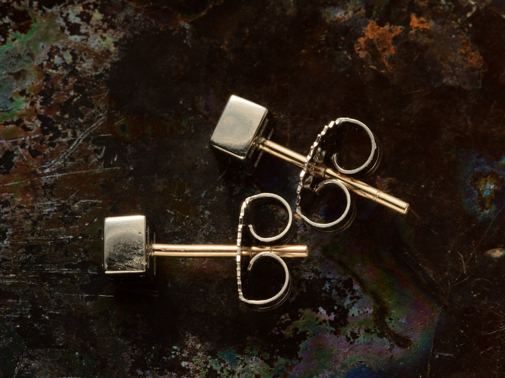 Side view of 0.35cttw Square Step Cut White Diamonds in Platinum Bezels with Yellow Gold Posts, Shown on dark textured background.