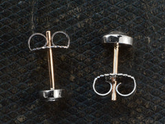thumbnail of Side profiles of a pair of mismatched and irregular shaped rose cut diamonds set in platinum bezels as stud earrings with 18K yellow gold posts and 18K white gold butterfly backs, shown on dark textured background