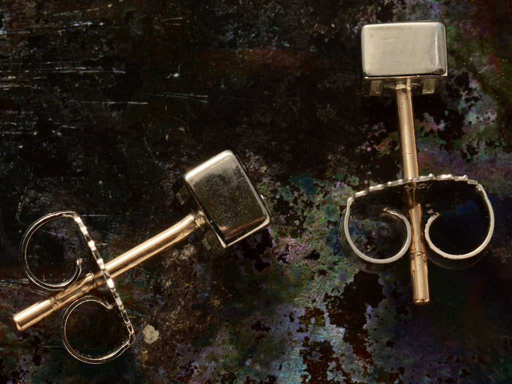 Sides of a pair of 0.52cttw Square Step Cut Diamonds Studs in Platinum Bezels with Yellow Gold Posts (on dark textured background)