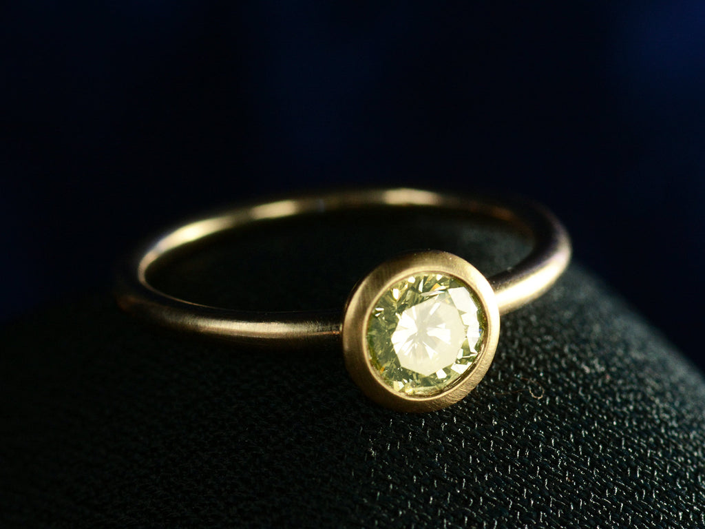 Angled front view of EB Modern engagement ring with 0.59ct Green-Yellow round diamond in yellow gold (on dark background)