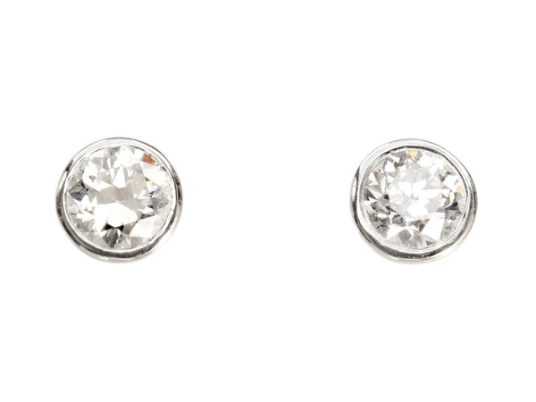 A pair of EB Modern stud earrings with platinum bezels and round white old cut diamonds. Shown on white background.