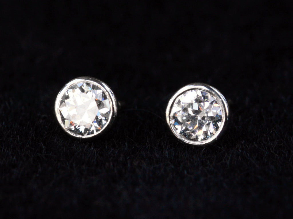 Detail view of EB Modern stud earrings with platinum bezels and round white old cut diamonds. Shown on black background.